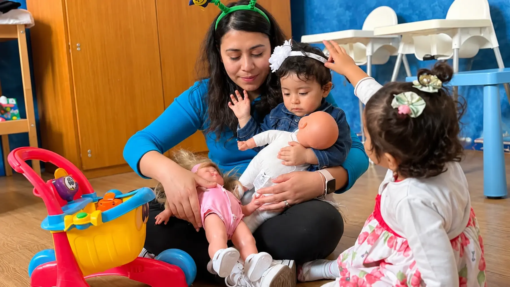 Una maestra con tre bambini piccoli che giocano con le bambole