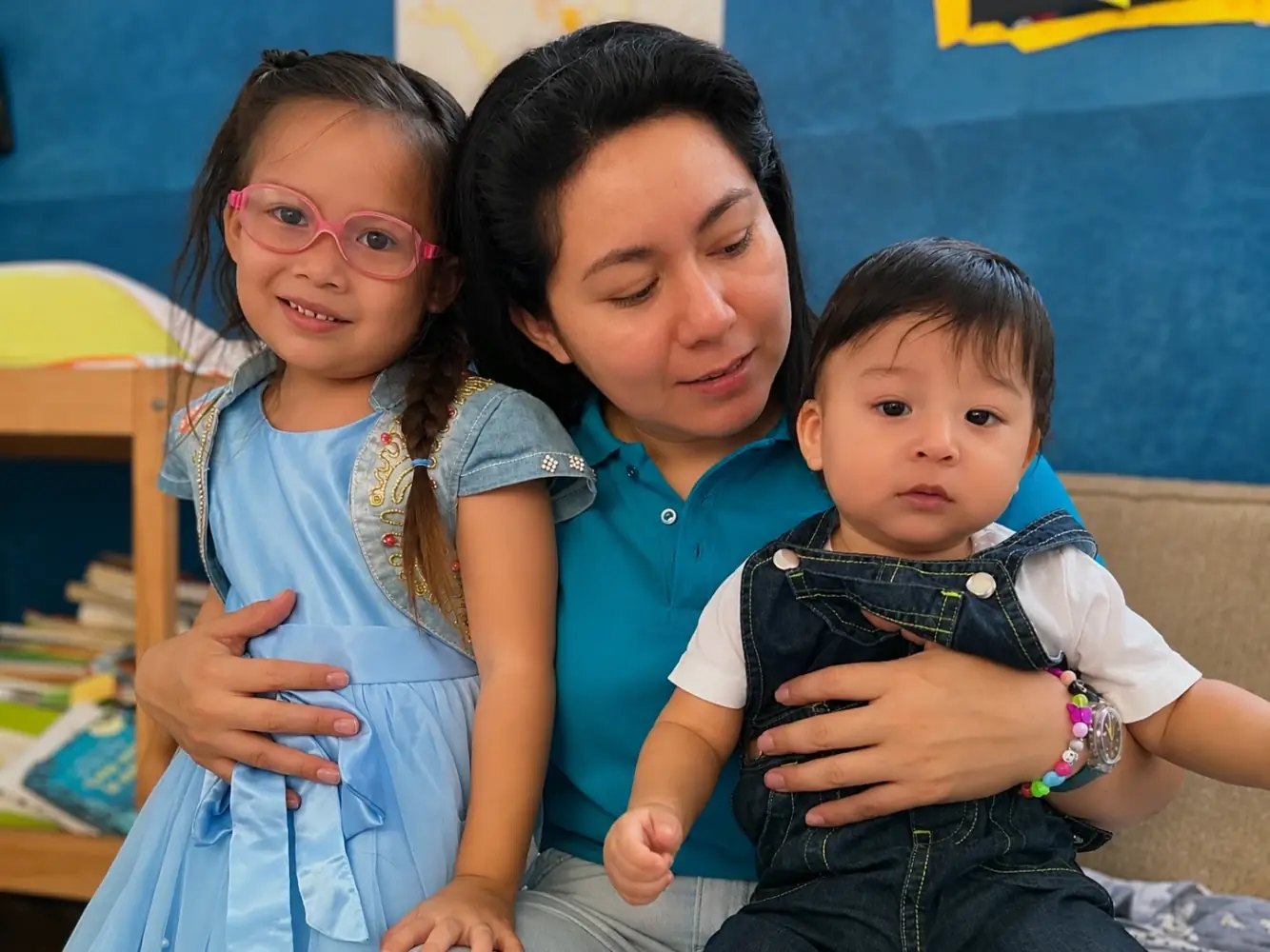 Una bambina con gli occhiali, una maestra e un bambino piccolo